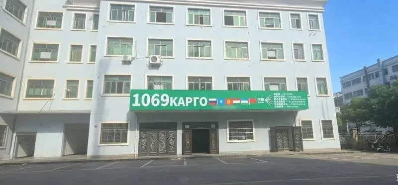 Здание склада в Иу с зелёной вывеской «1069 КАРГО»